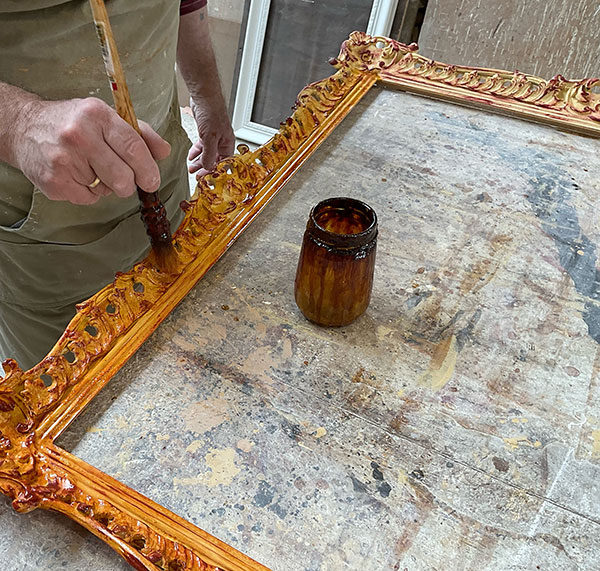 Master frame maker James Dickins applies Button polish to a 3 inch Chippendale picture frame before applying metal leaf. 